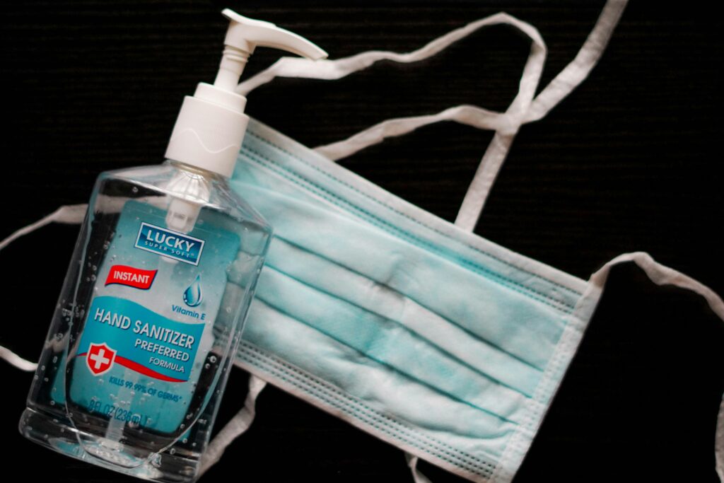 A blue face mask next to a bottle of hand sanitizer. 