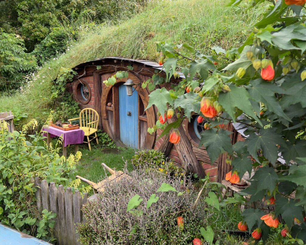 A blue door Hobbit hole with a small chair in front and garden.