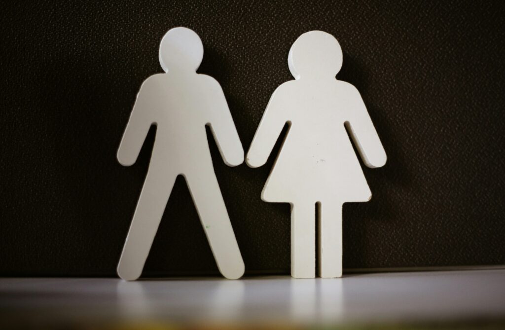 Gendered paper cut outs of a man and woman standing next to each other.