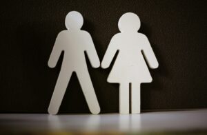 Gendered paper cut outs of a man and woman standing next to each other.