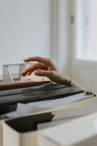 A woman’s hand reaches into a filing cabinet hesitantly. It almost looks like her hand is coming to the surface of a body of water that she is desperately trying to escape.