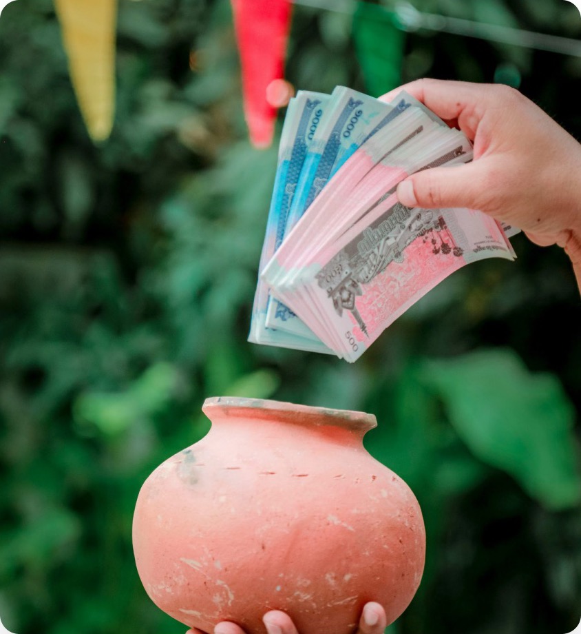 Hands placing money into a clay pot