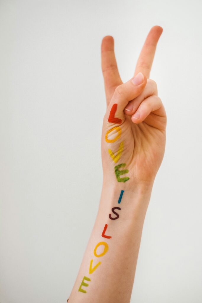 “Love is Love” written as a spectrum ‘tatoo’ on arm