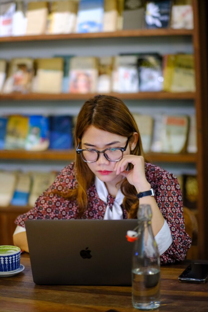 Young woman working focused on a laptop in a cozy cafe setting in Hue, Vietnam.
